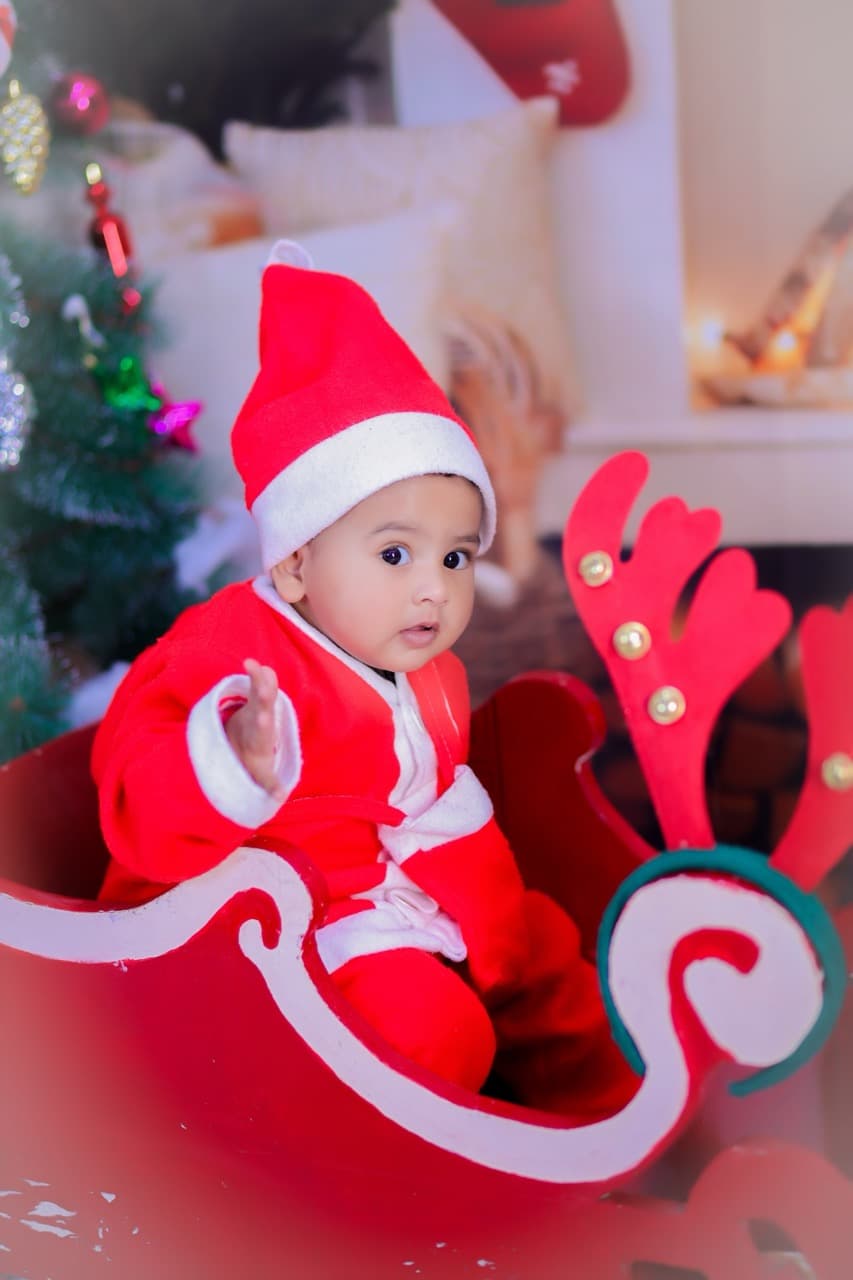 Baby in red holiday outfit with festive ornaments