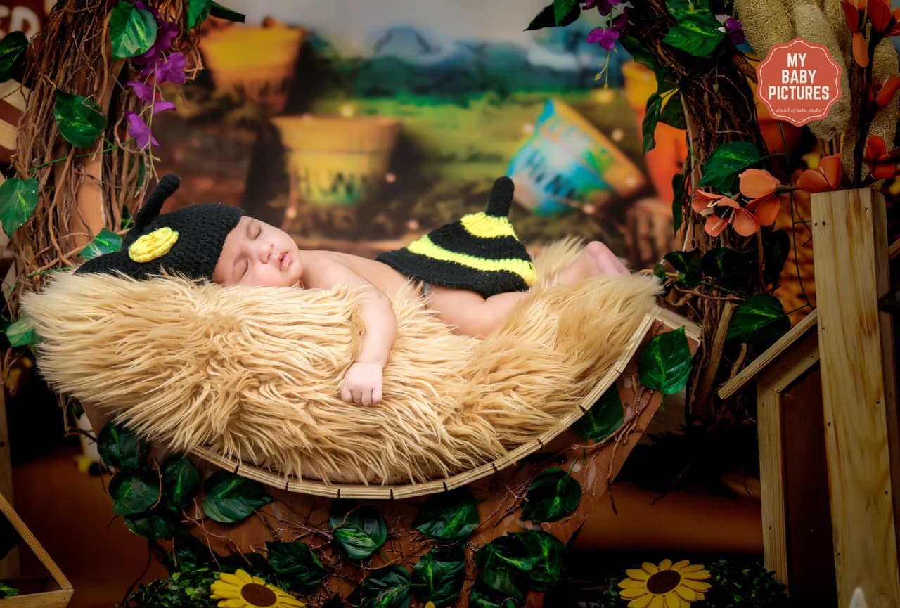 Sleeping newborn in bee theme setup with gentle posing