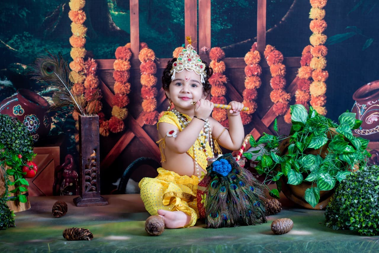 Baby in Krishna costume playing flute for milestone session